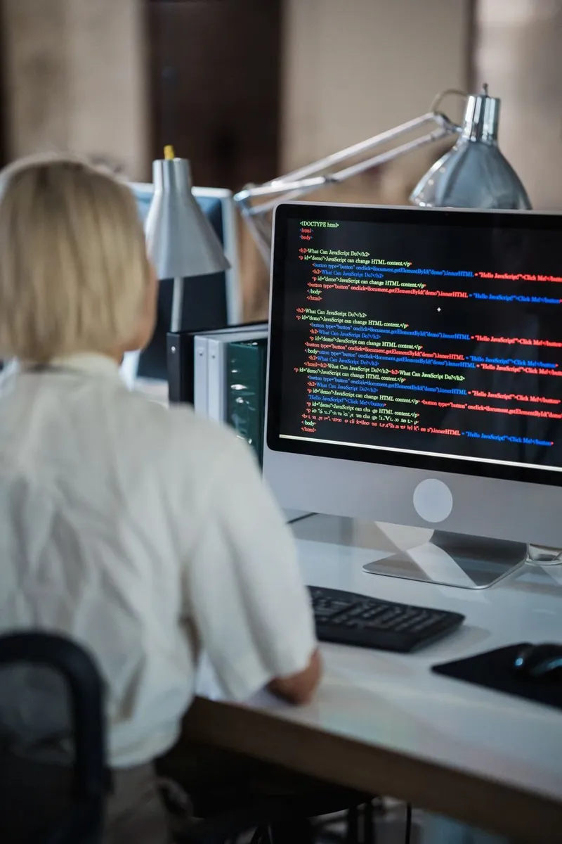 An engineer reviewing AI system configuration across two bright office monitors