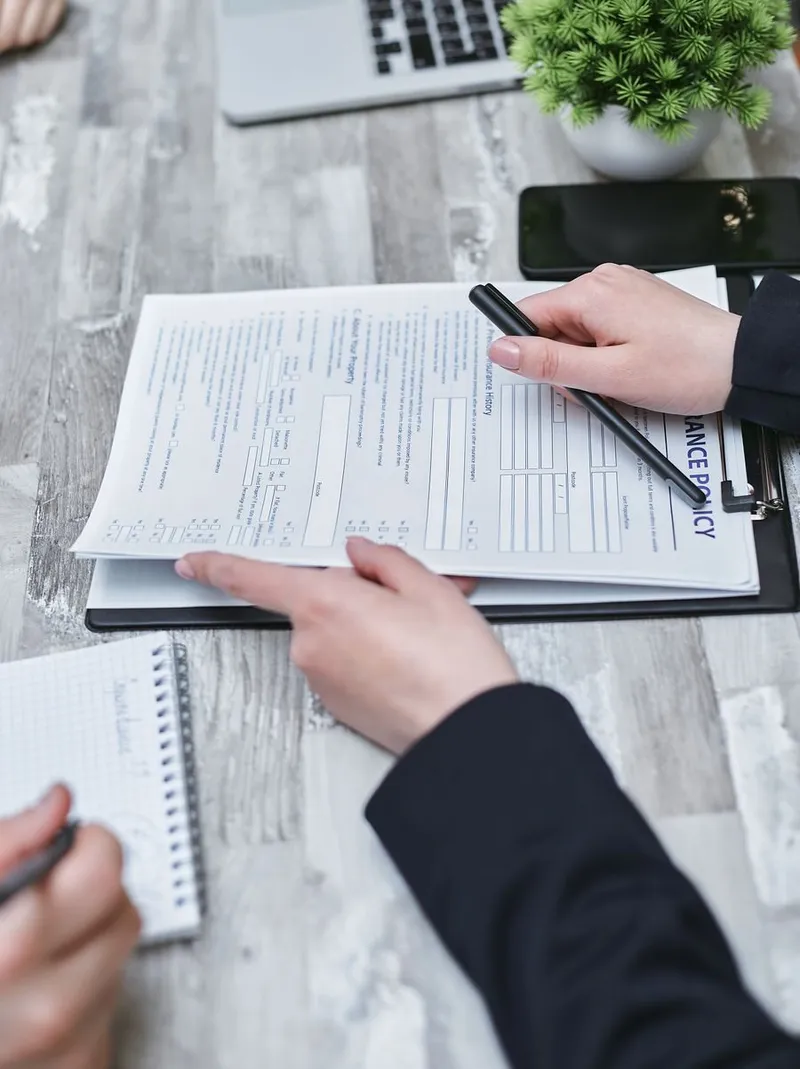 Hands reviewing compliance paperwork with a pen on a bright desk