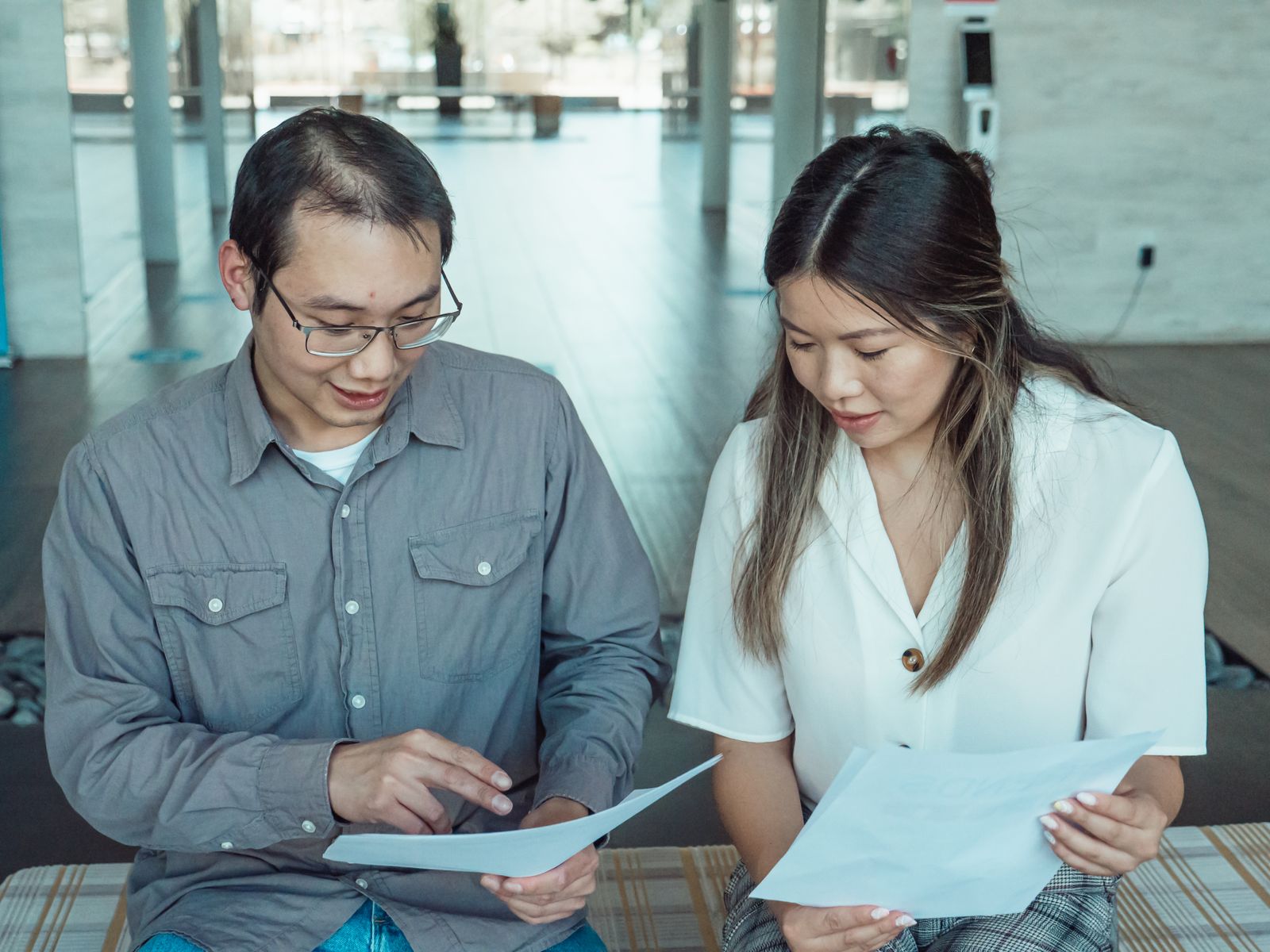 Two colleagues reviewing compliance documents together in a bright office
