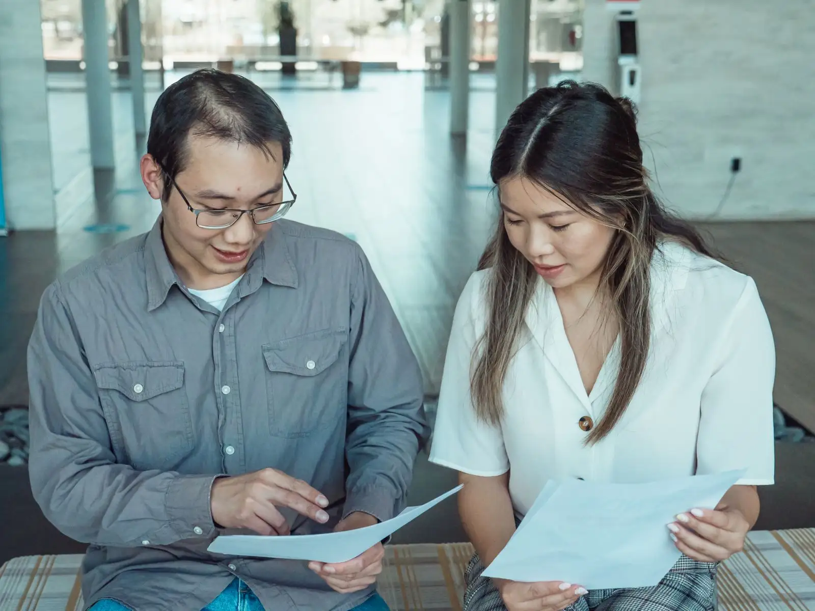 Two colleagues reviewing compliance documents together in a bright office