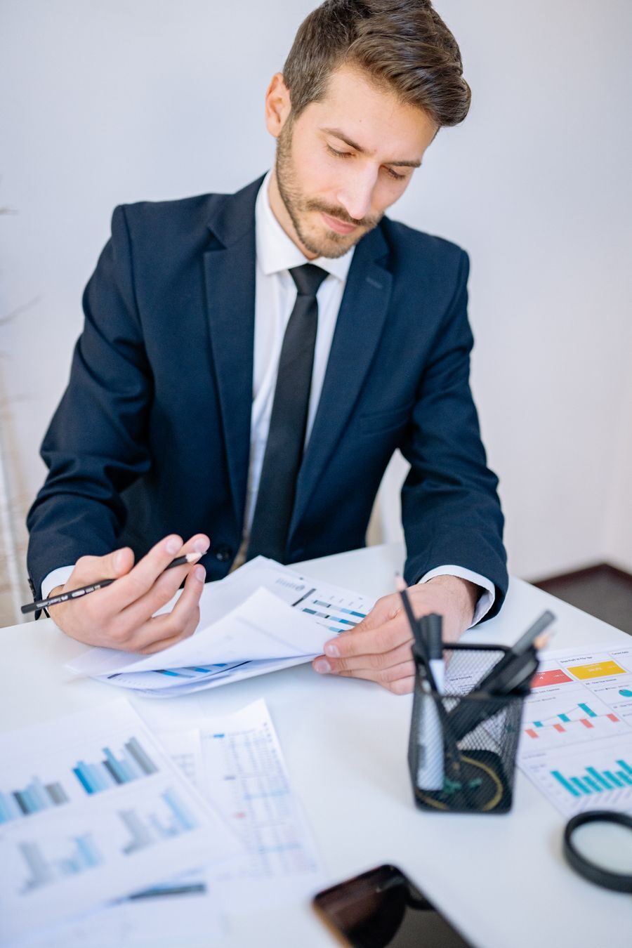 A businessman reviewing financial charts at his desk in a bright office