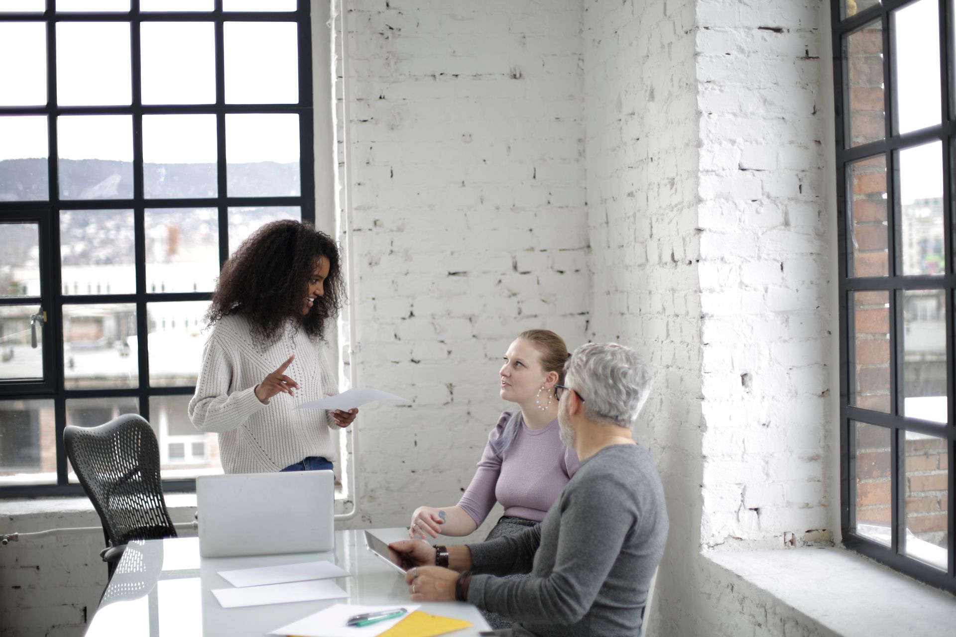 Colleagues discussing documents around a laptop in a bright, spacious office