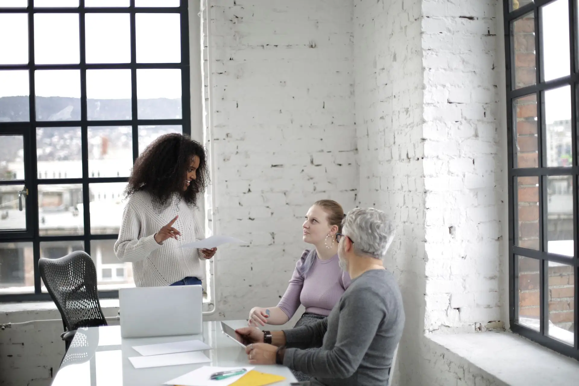 Colleagues discussing documents around a laptop in a bright, spacious office