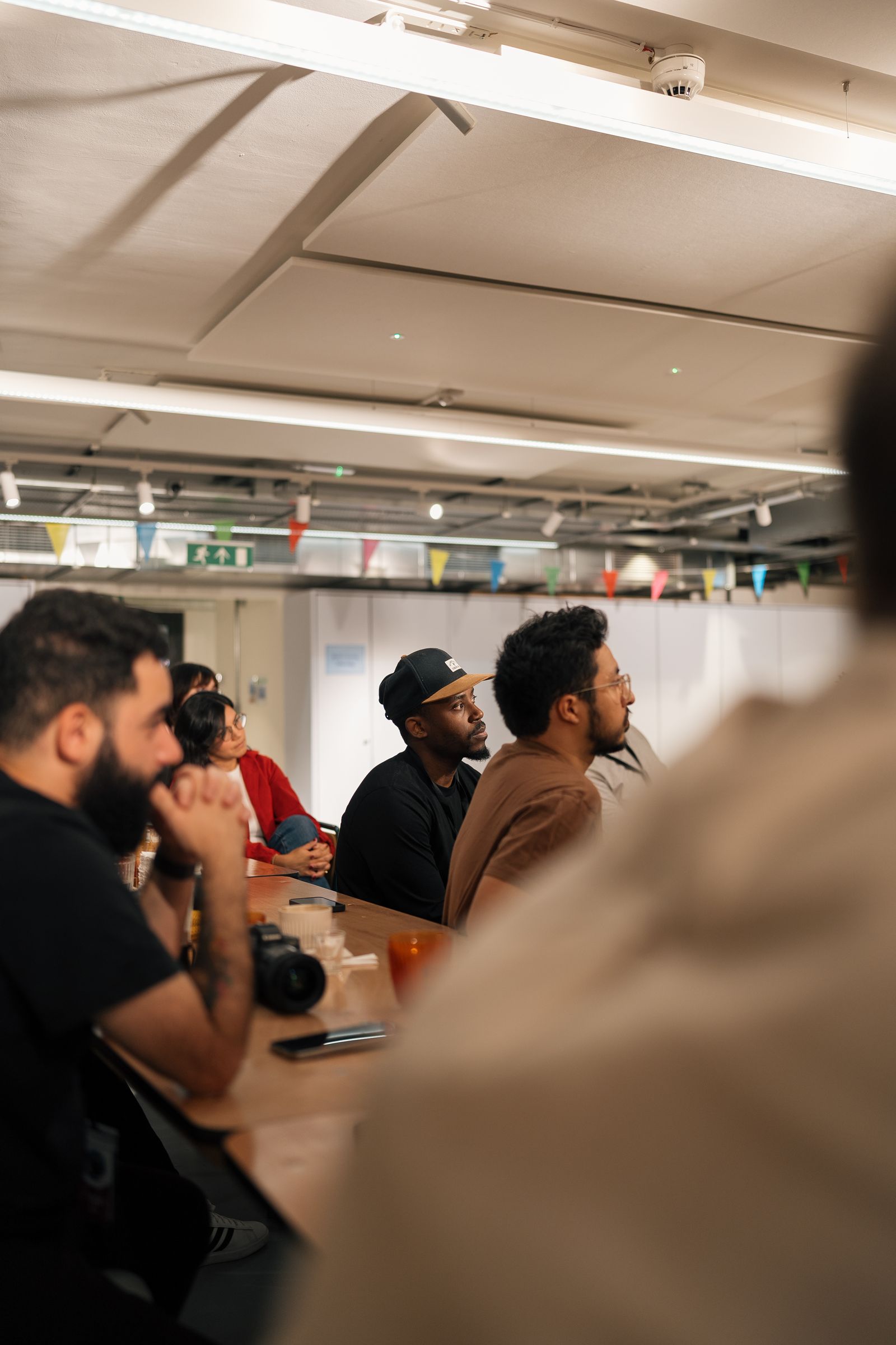 People seated at a table during a meeting in an office with bunting and a camera on the table