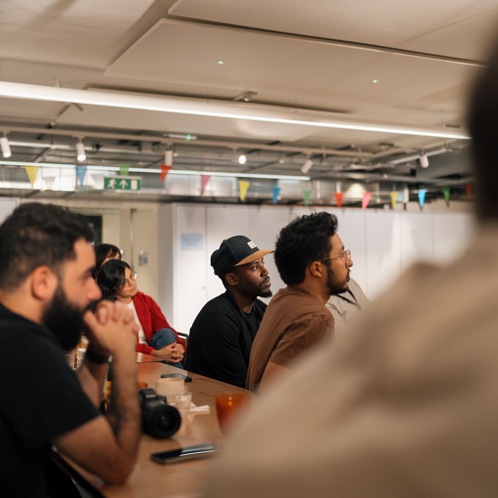People seated at a table during a meeting in an office with bunting and a camera on the table