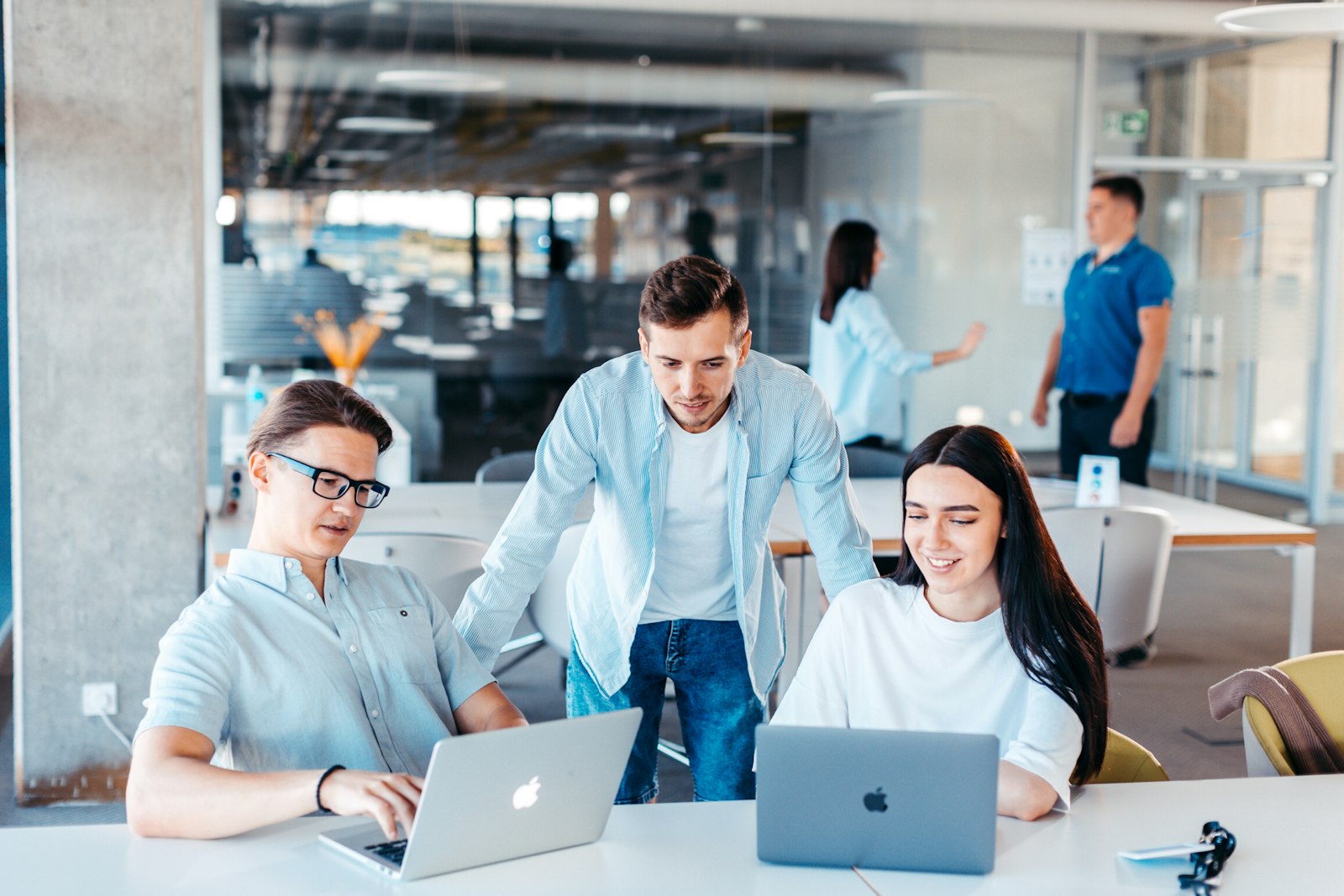 Three colleagues working at laptops in a bright open-plan office
