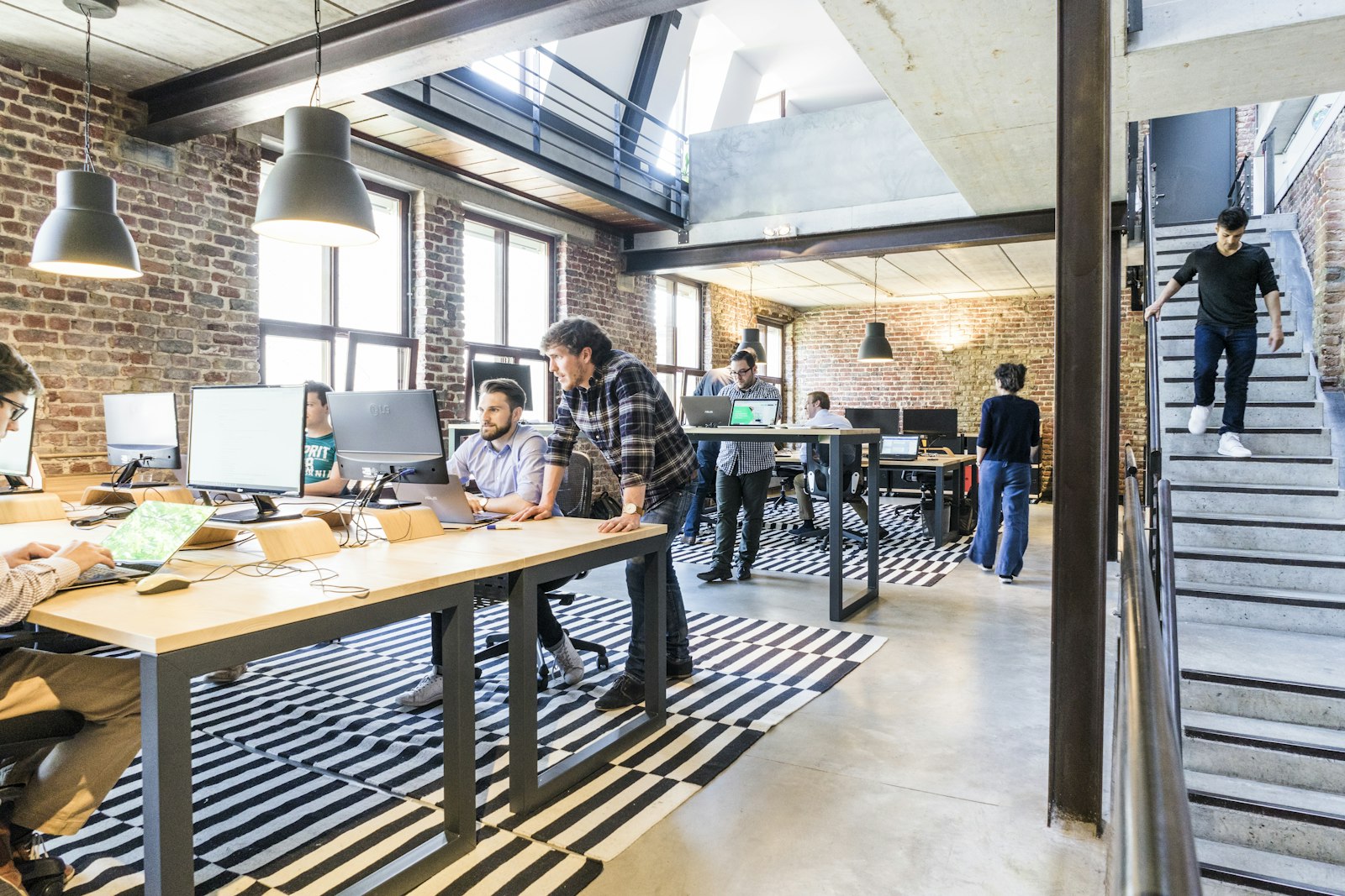 A busy loft-style office with brick walls and people working at desks