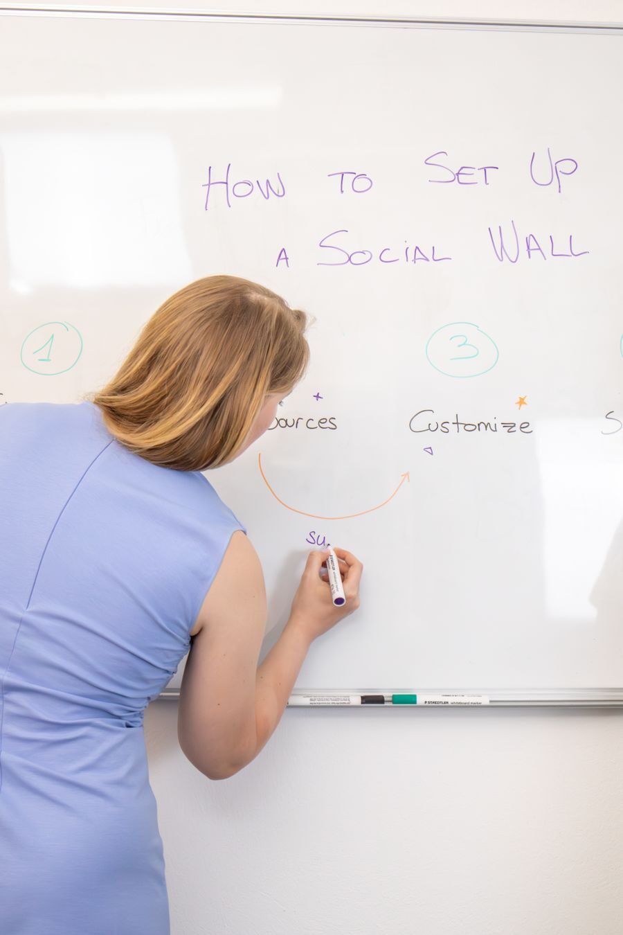 A facilitator mapping out a strategy on a whiteboard during a bright office workshop