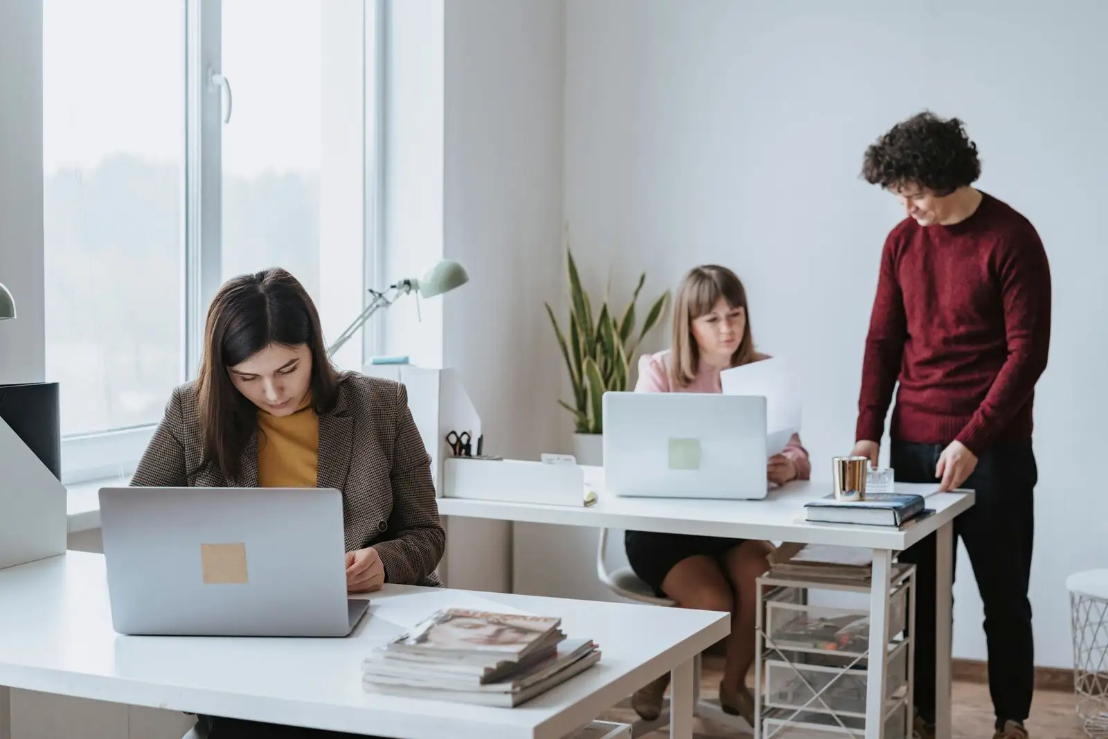 Four colleagues working together on laptops in a bright modern office
