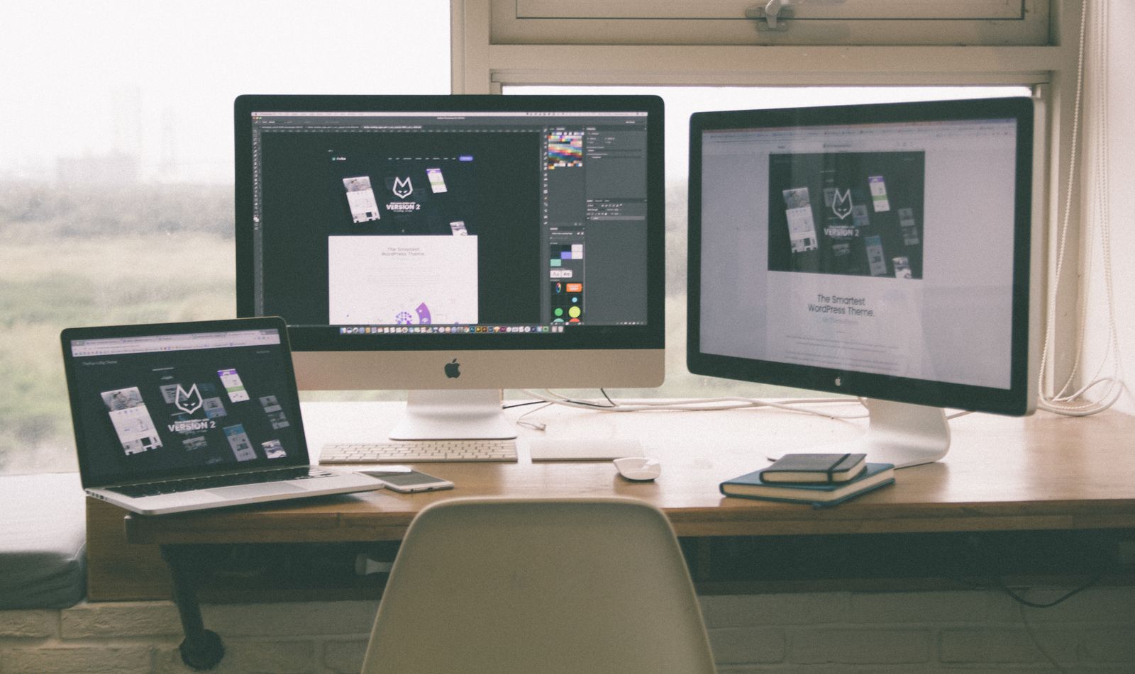 Web design project open across a laptop and monitors on a bright office desk